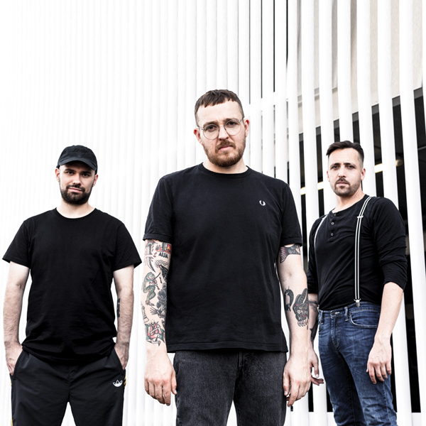 Antilopen Gang Titelbild. Die drei Musiker in schwarzem Shirt blicken in die Kamera.