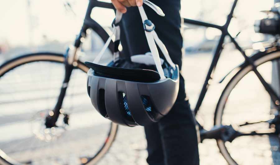 Fahrrad und sein Fahrer (bis zum Oberkörper) mit Unschärfe, der Fahrradhelm groß und im Fokus.